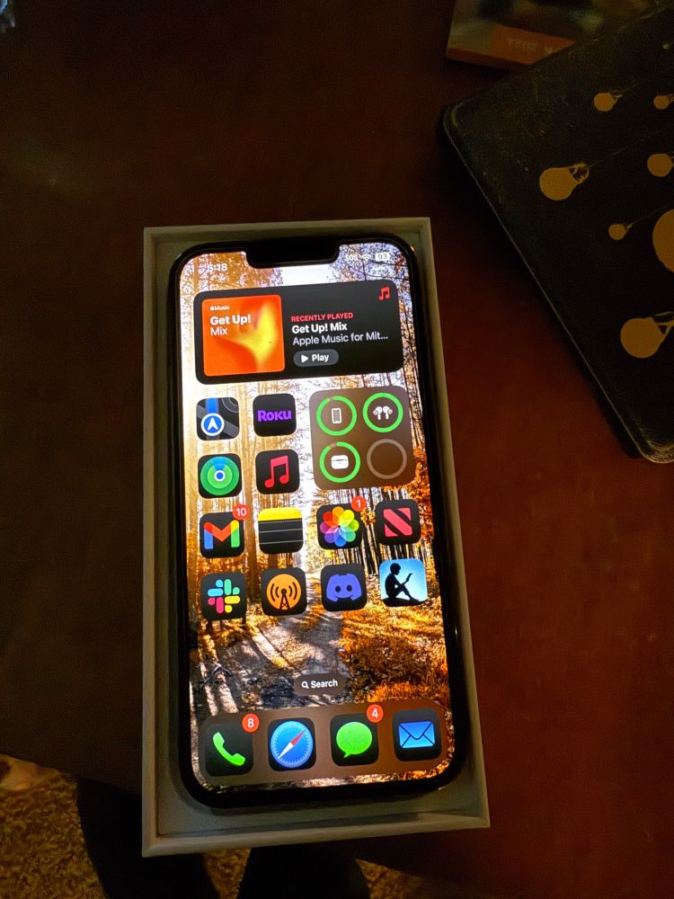 An iPhone 13 Pro in a box. A Home Screen full of icons is displayed 