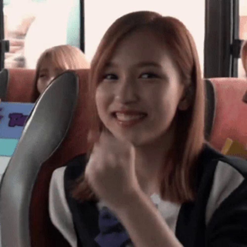 a girl with red hair is sitting in a bus and smiling