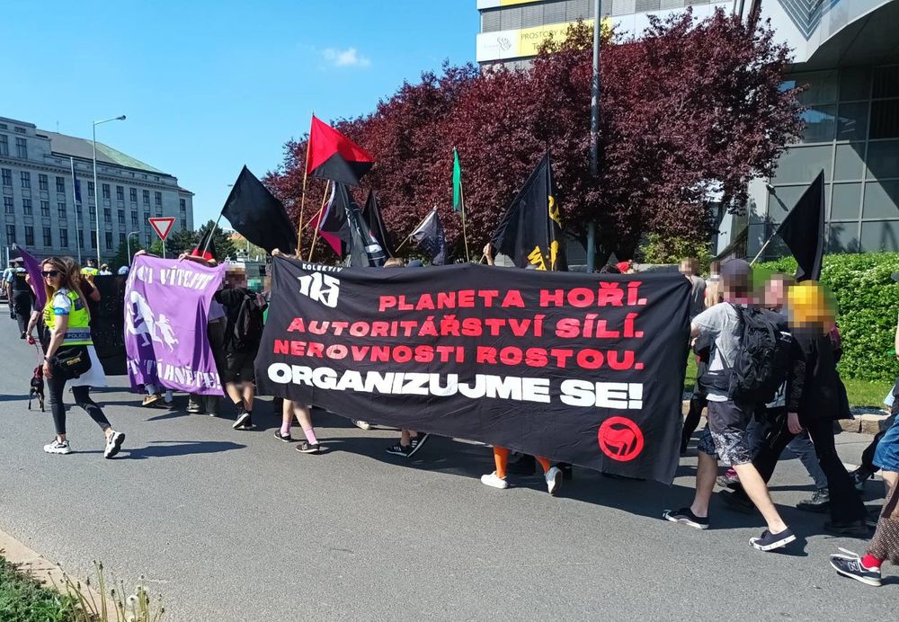pochod s plejádou vlajek a bannerem 'Planeta hoří. Aurotitářství síly. Nerovnosti rostou. Organizujme se!" Kolektivu 115