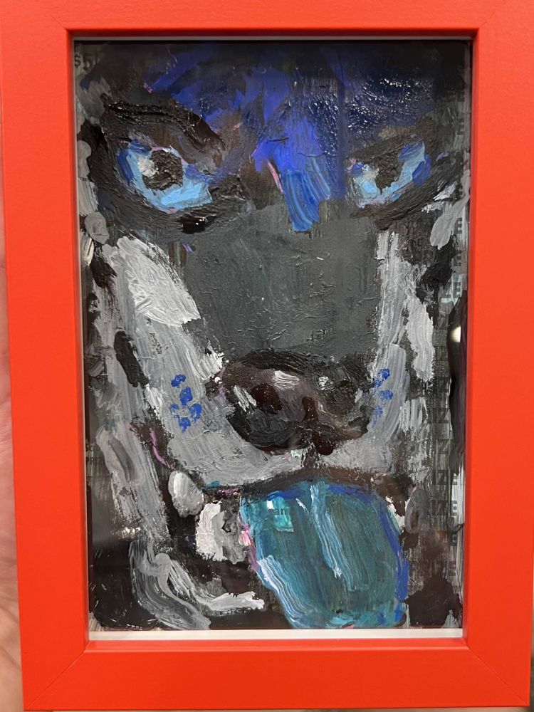 Painting in a red frame. The image on the painting is of a closeup shop of a wolf with blue eyes, blue hair, and blue tongue, looking at the viewer. 