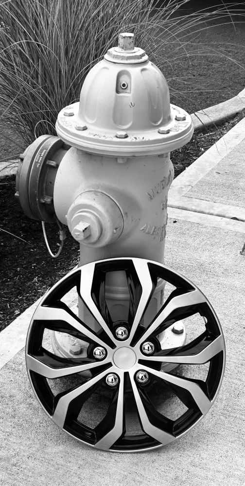Fire hydrant with lost wheel cover propped against it on the curb