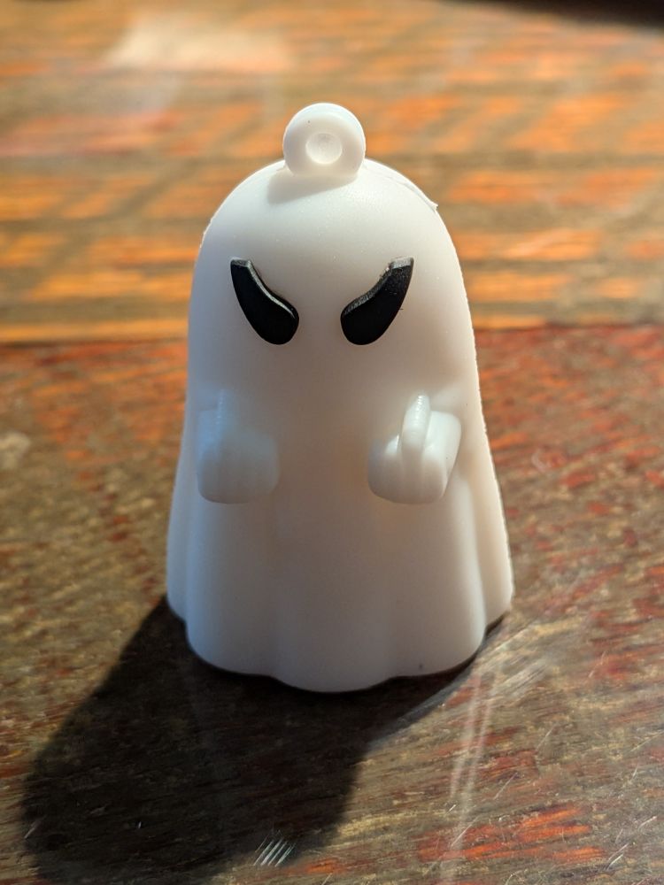 Small white plastic ghost figurine with an angry face flipping the bird with both hands