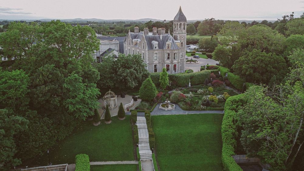 Aerial photo of the conference hotel a large stone manor nestled in green trees and lawn.