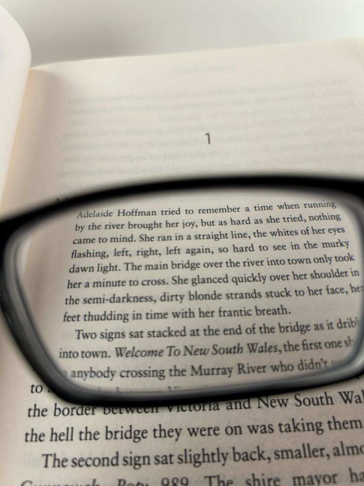 Looking through one side of a pair of glasses at page 1 of a book.