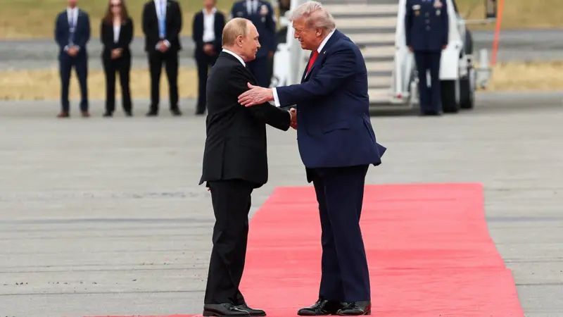 Trump, Putin, red carpet, puke, shaking hands, doing body language acting, pathetic. Reuters photograph from the BBC News site.