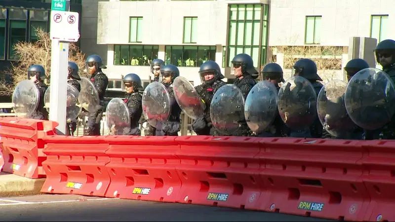A road barrier, a line of police bastards behind it, shields helmets.