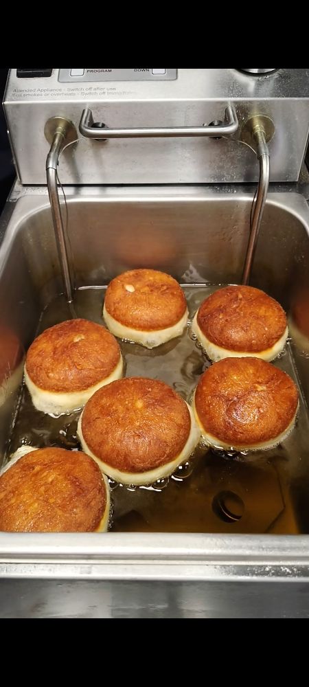 6 round doughnuts browned on one side cooking in oil