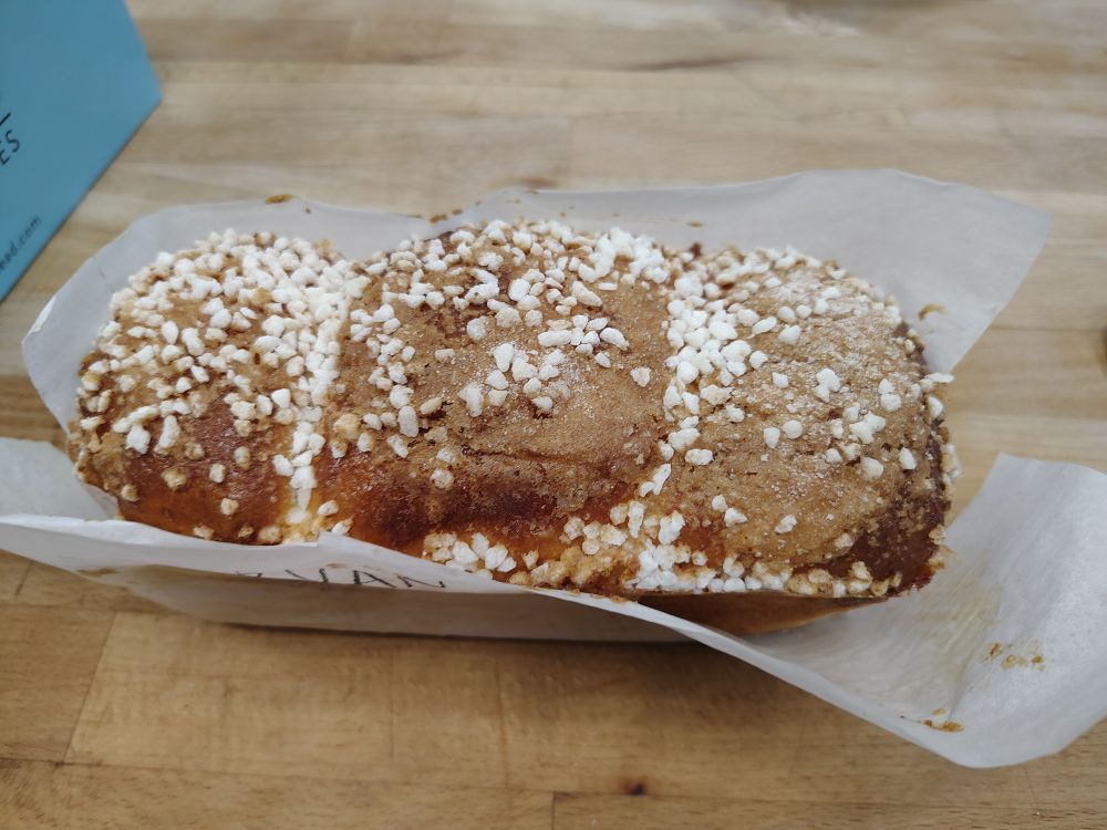 A baked glazed brioche loaf covered in sugar nibs