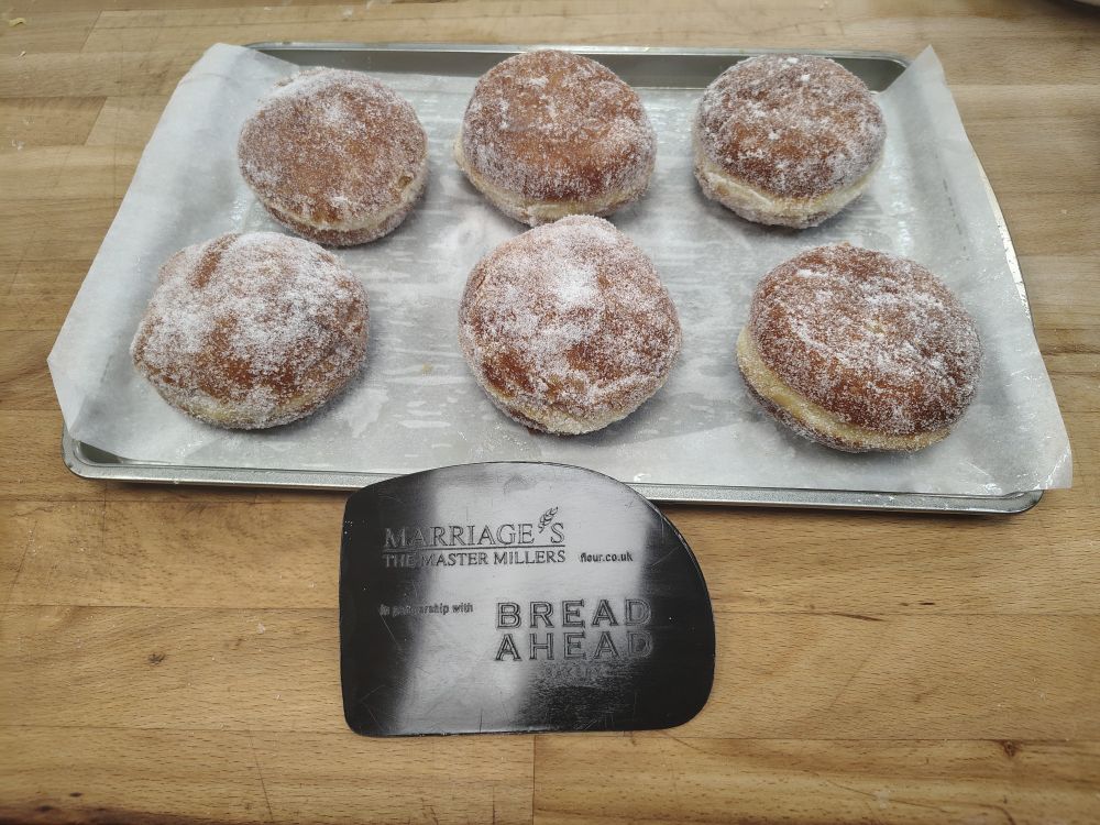 6 round doughnuts dusted in sugar and a Bread Ahead dough cutter