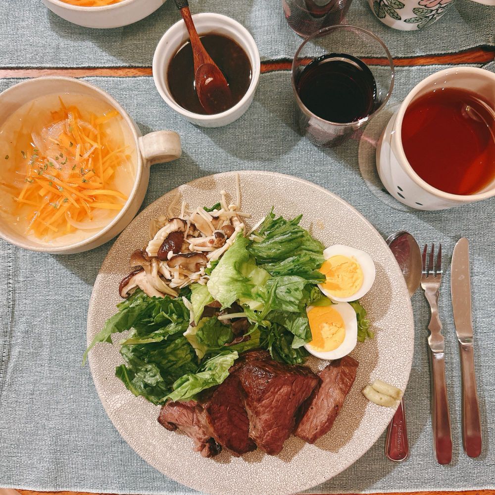 ワンプレートご飯とスープ。切り分けられた牛肉のステーキとゆでたまご、レタス、きのこのマリネがワンプレートに盛られている。
