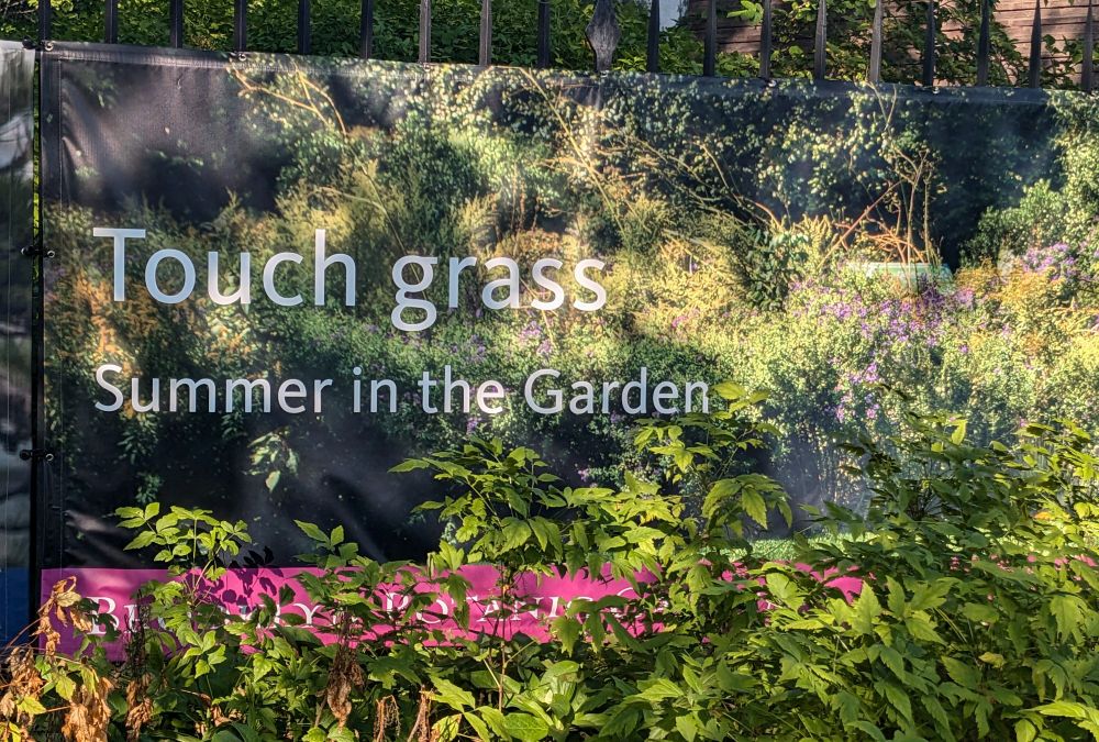 a printed banner for the Brooklyn Botanic Garden with the tagline "Touch Grass - Summer in the Garden" 
