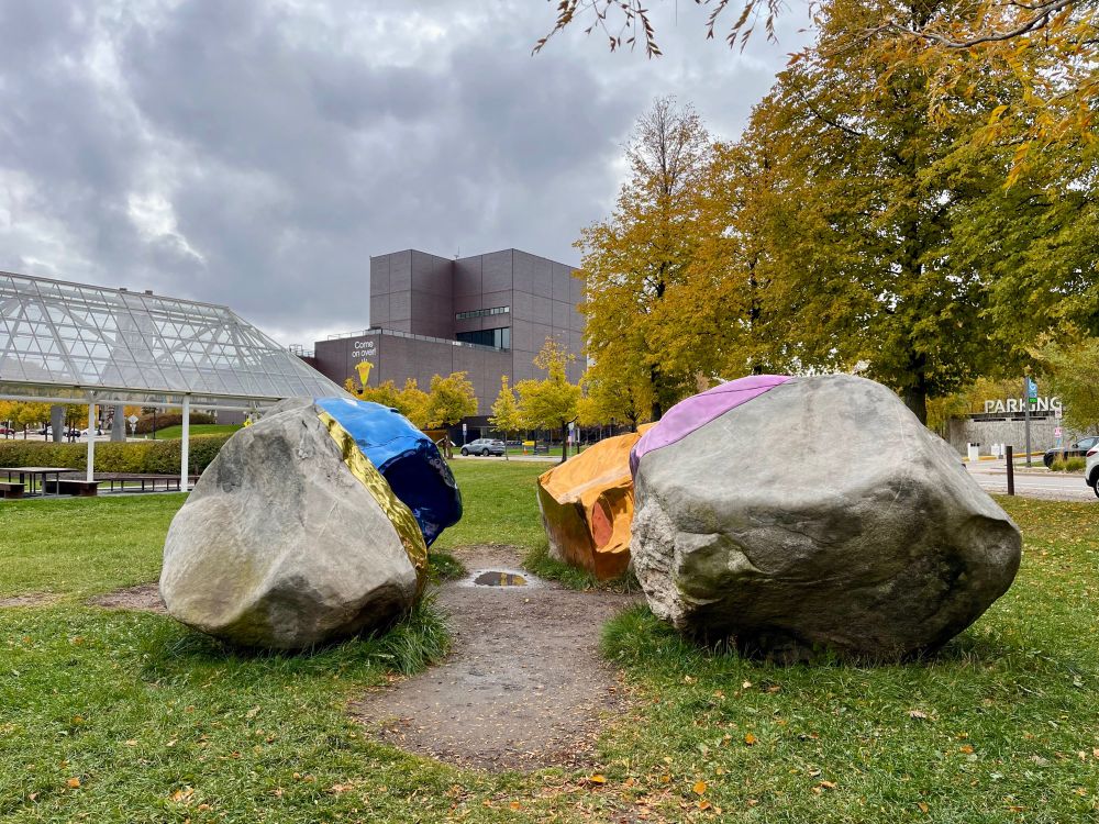 A view of the Walker from the sculpture garden, sculptural rocks with colored facets are in the foreground.