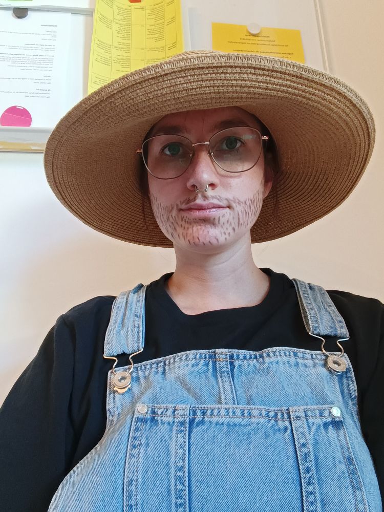 Foto von mir mit Latzhose und aufgemalten Bart und einem Strohhut, ich bin ein Gärtner 