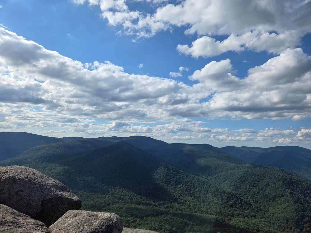 rolling green hilly mountains with cumulus clouds overhead