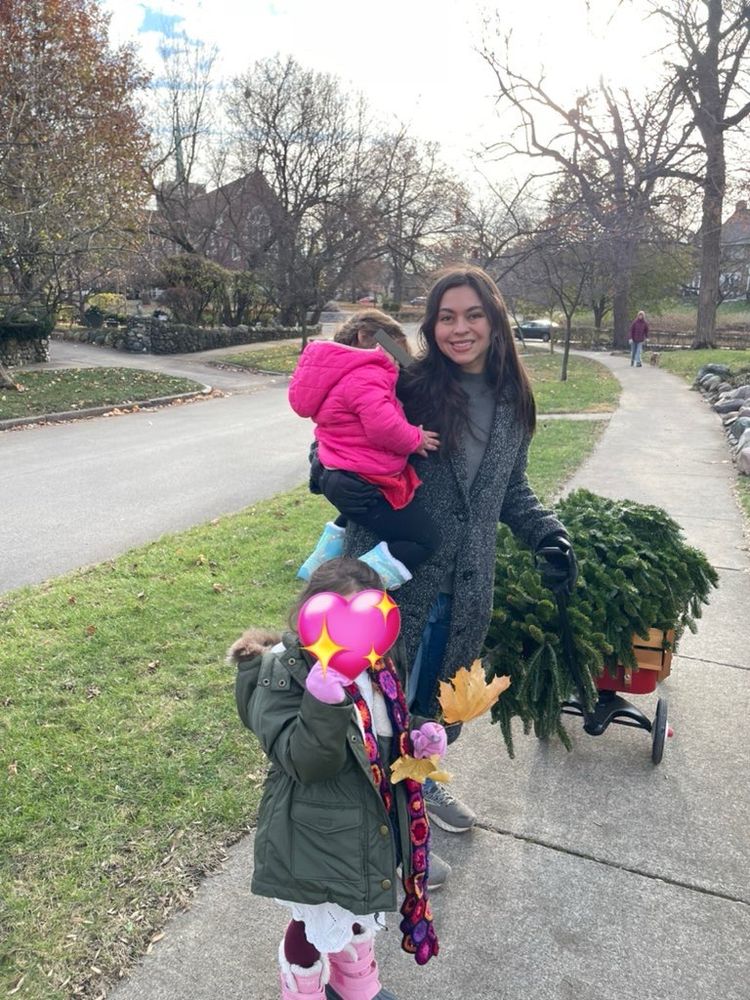Photo of a woman hauling not only a Christmas tree on a wagon but also a sleeping todder