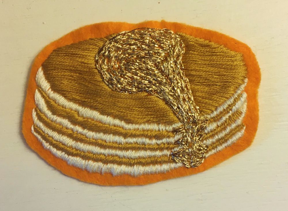 Embroidered pile of pancakes topped with syrup. 