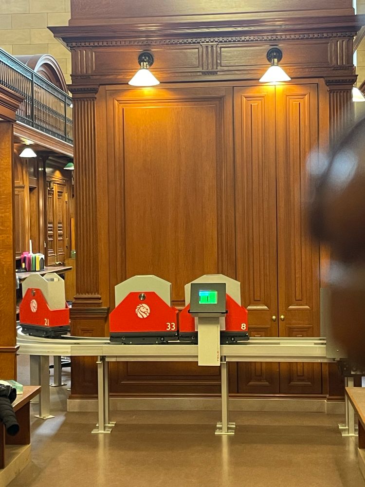 Small red carriages on wheels which deliver books from library storage.