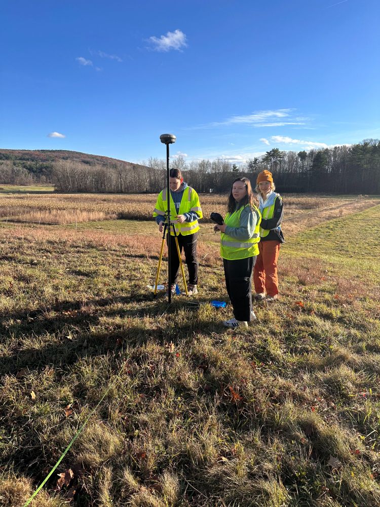 3 people collecting surveying data in open field