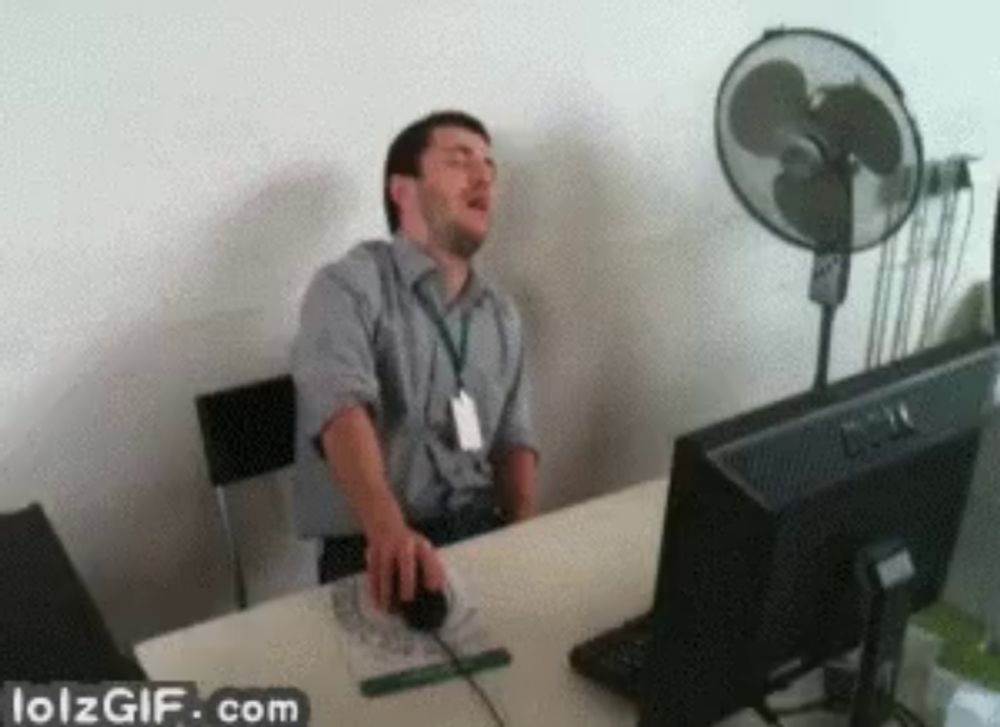 a man sitting at a desk with his eyes closed and a lolzgif.com watermark