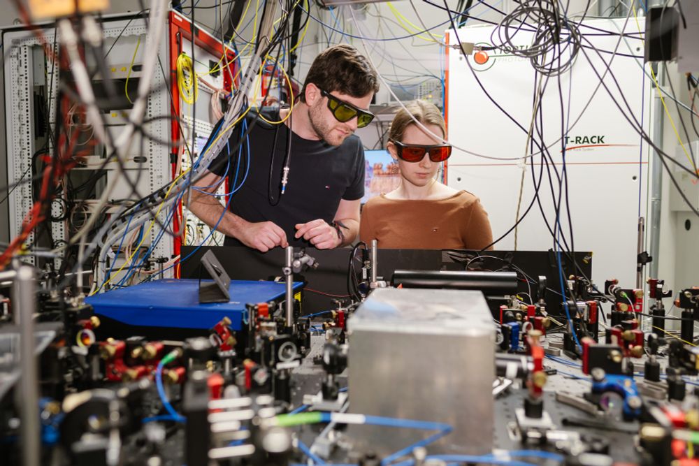 Ein Forscher und eine Forscherin arbeiten an einer Laserapparatur im Quantenlabor.
