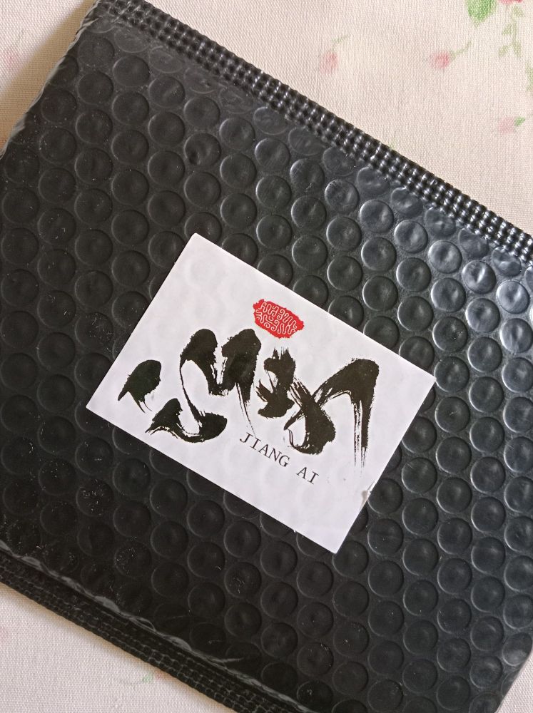 One side of a package with a sticker on it, on which "Jiang Ai" is written. 