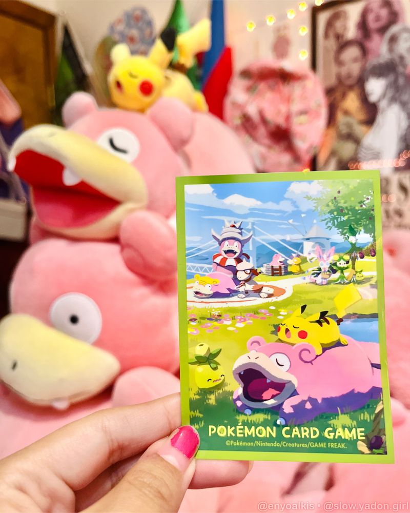 Pokémon Center Kagawa card sleeve with the yawning Slowpoke and Pikachu plush in the background