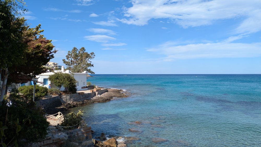 Glass-clear Cretan seawater, a small white house overlooking it.