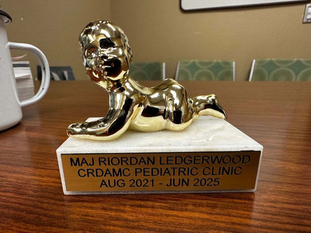 A picture of a small trophy with a golden plastic baby whose face looks like it’s split into two