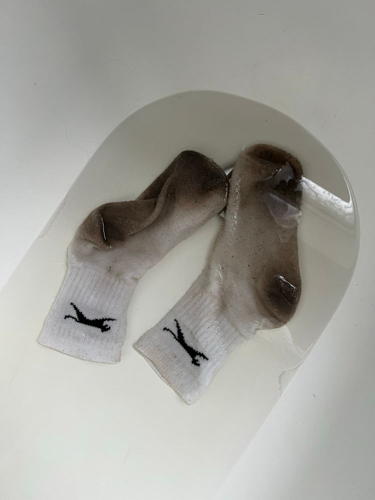 A pair of very dirty white socks soaking in a bath, which didn’t come clean