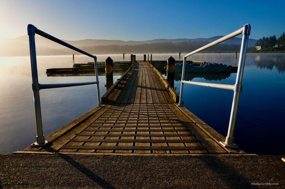 Photo of boat dock on Devils Lake, Lincoln City, Oregon. Viewed from just in front of dock, looking toward the lake. 