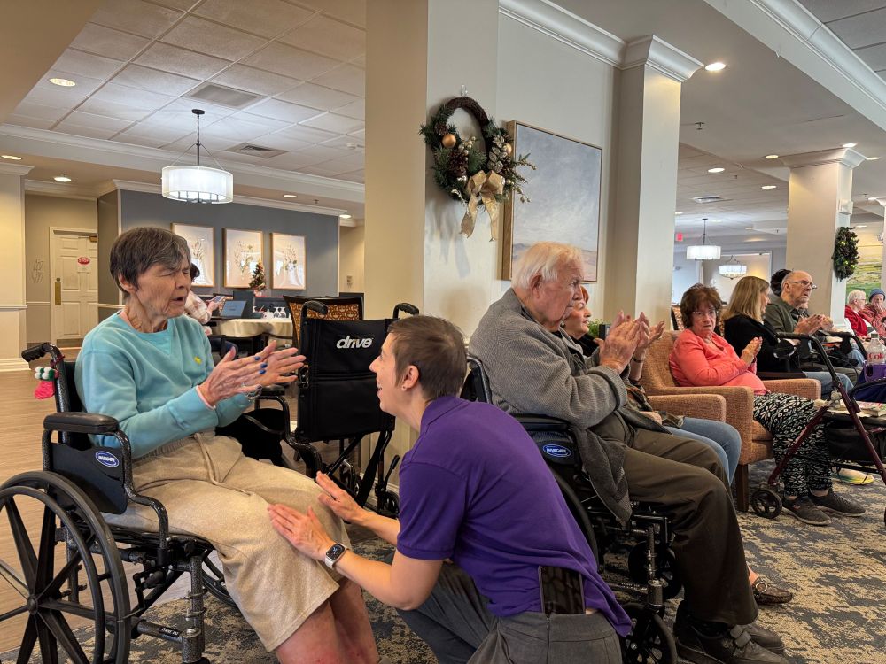 A woman kneels and sings to a woman sitting in a wheelchair.