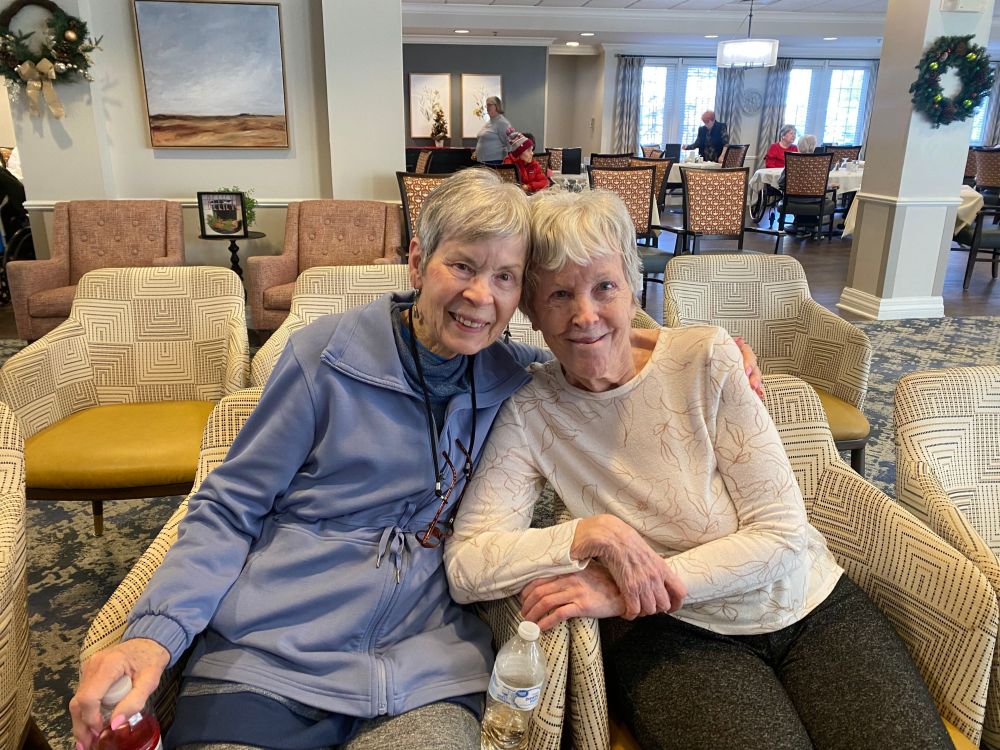 Two women sitting in chairs and smiling at the camera.