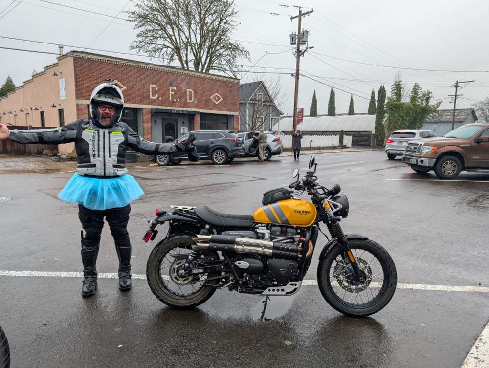 Motorcycle rider in a tutu next to a Triumph Scrambler 900.
