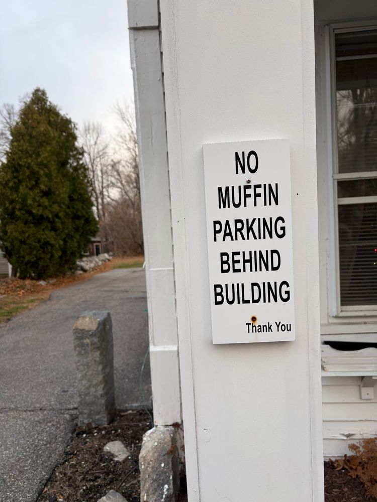 A sign that reads “no muffin parking behind building”
