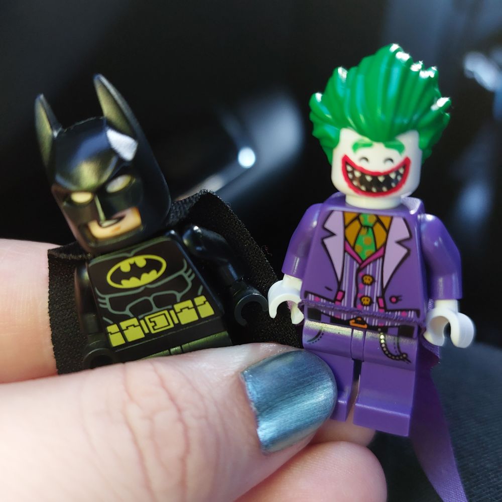 A hand holding Lego Minifigures of Batman and Joker from the Lego Batman movie
