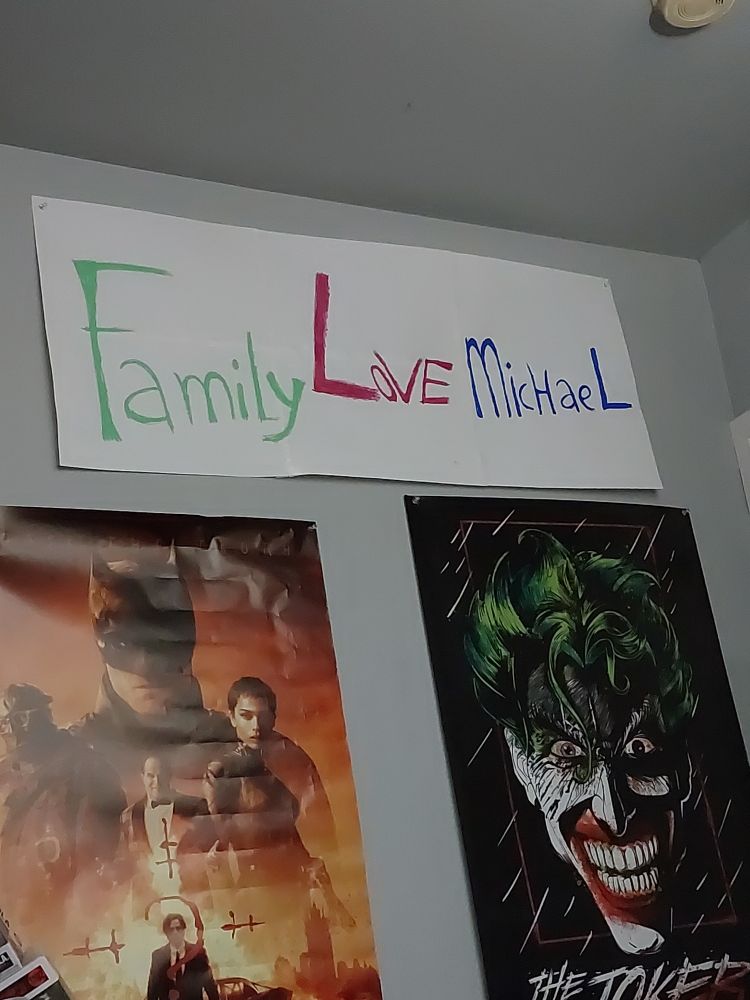 A banner on my wall in my bedroom that says "Family love Michael" like the banner from Arrested Development. Below is a poster of the Joker and another poster for The Batman starring Robert Pattingson