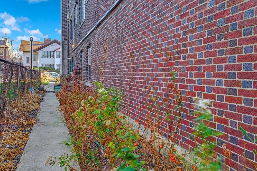 Color photo of BRICK side of apartment building in Flemish bond, alternating red stretcher and dark blue headers. Saturation hyped in photo program.