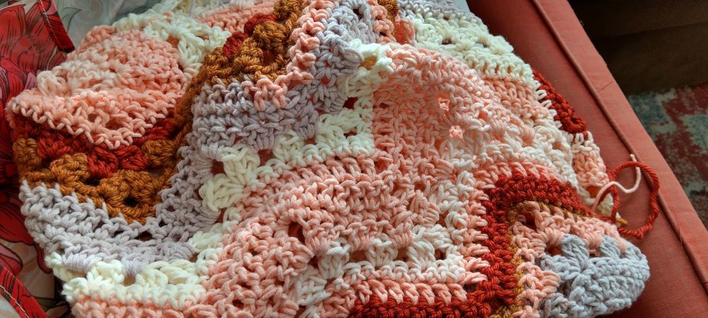 Crochet baby blanket in peach, rust, and cinnamon ripple stripes using the pattern for the six day blanket