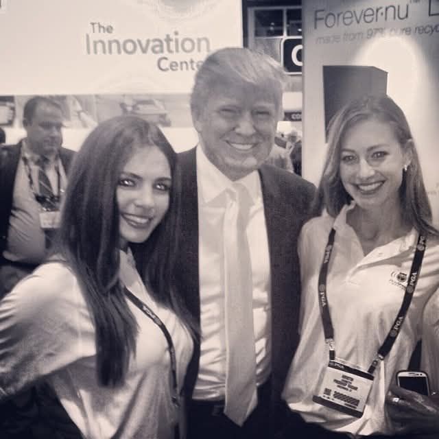 Jessica Ashley Deluge and another model are standing with Donald Trump at a conference, understanding him to be a benefactor of beauty pageants and eccentric businessman.