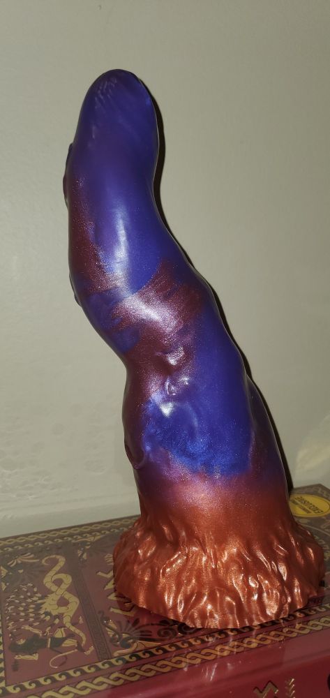 The image contains a dildo from https://www.fantasticocks.com. The dildo is Taurus the Zodiac Bull, soft, "shimmery purple" shaft with "metallic copper" base, added marbled "shimmery wine" to shaft.