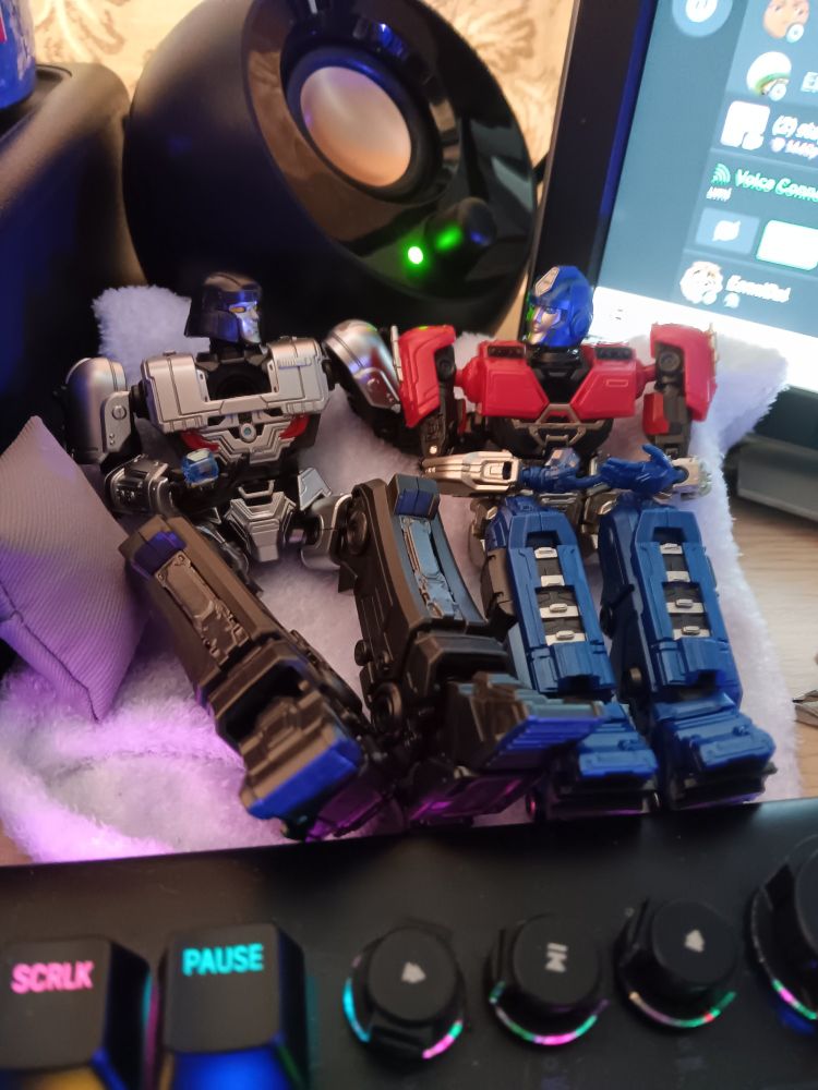 Yolopark cogless D-16 and Orion Pax sit side by side on white fluffy socks