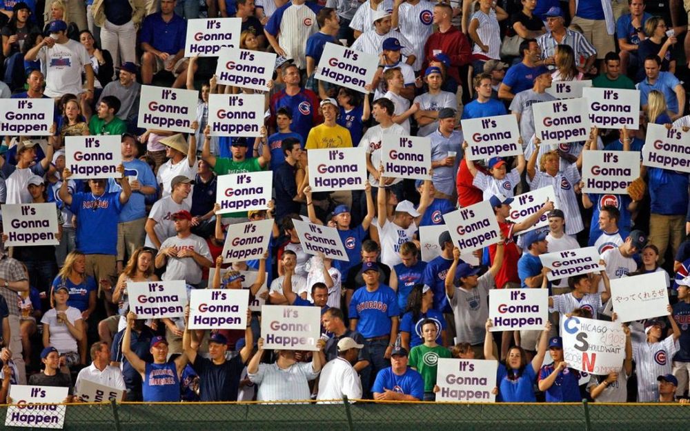 A bunch of people in the Wrigley Field bleachers holding signs that say “It’s Gonna Happen”