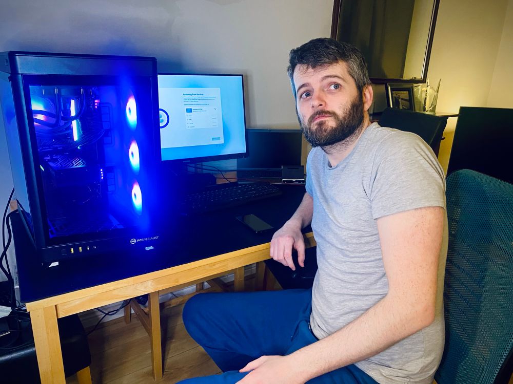 Gavin sitting at a desk with an ostentatious gaming PC beside him 