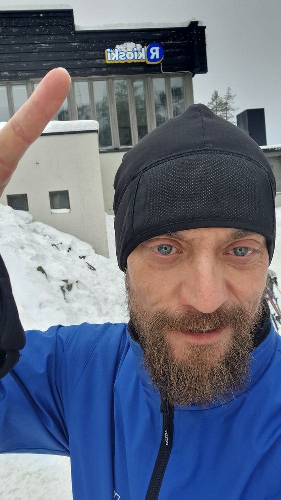 Selfie hiihtokamoissa. Osoitan kioskin kylttiä hotellin seinässä..