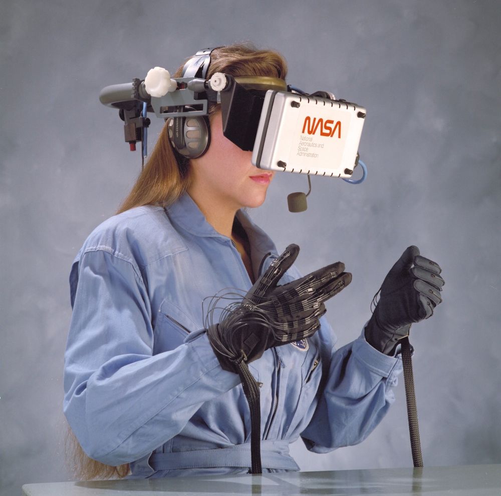 Blonde woman in jumpsuit using a NASA VR headset via haptic gloves