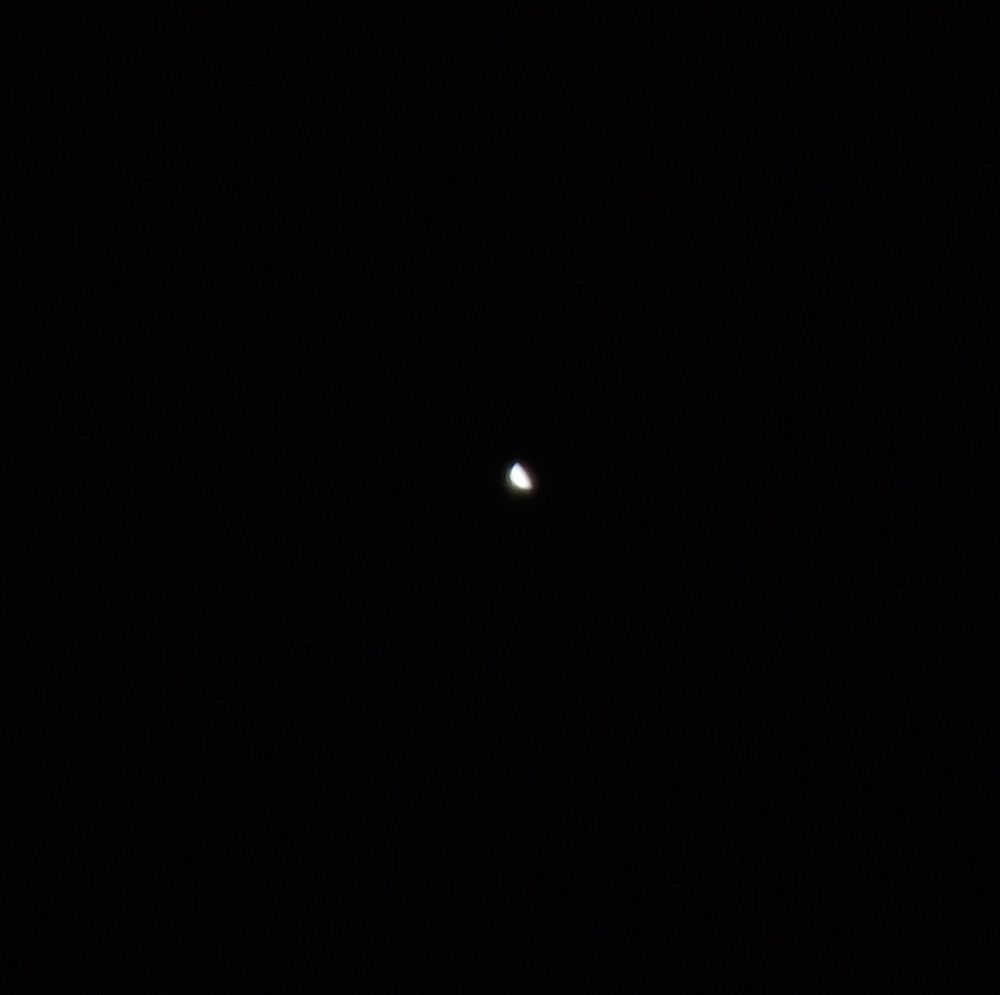 Venus through a telescope, looking like a tiny half Moon