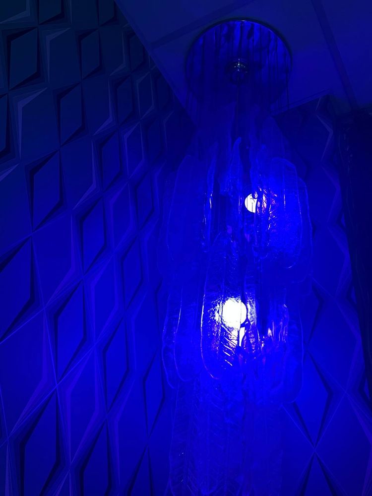 You see a wall with diamond shapes, everything is illuminated by a blue lamp.