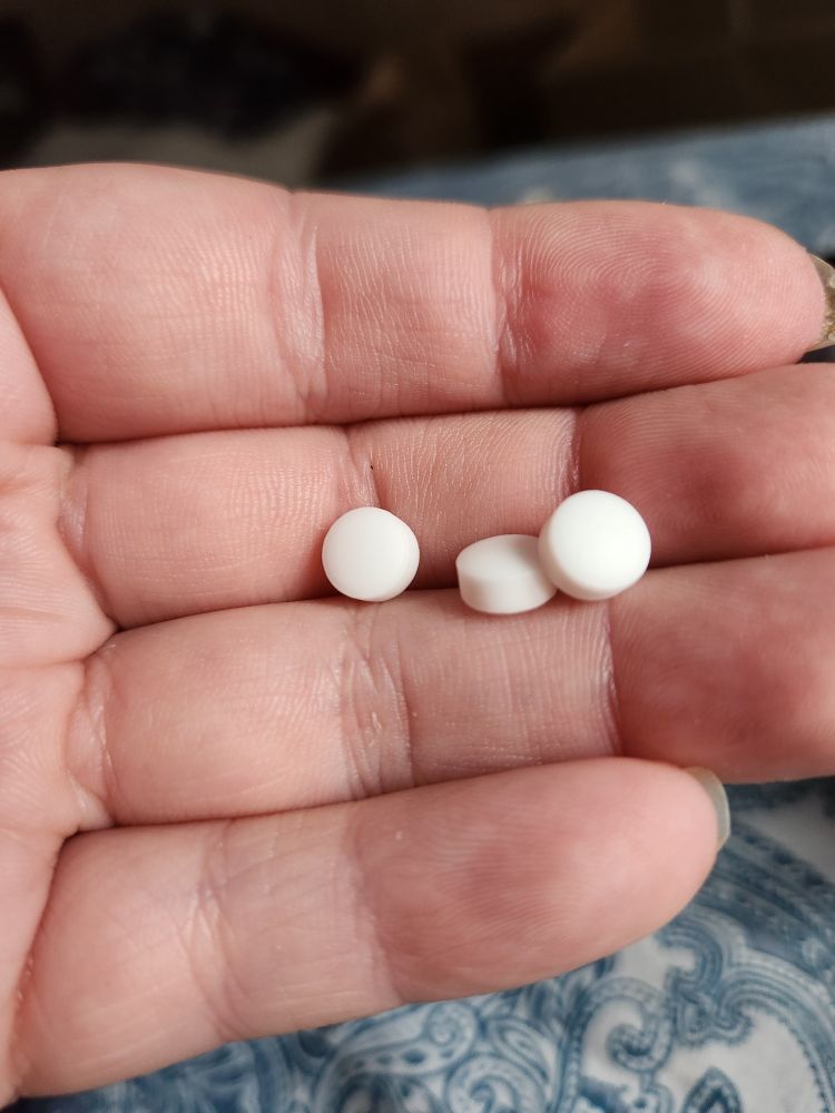 A close up of a hand with 3 white pills.