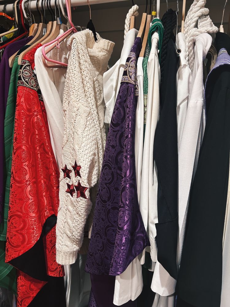the sacristy closet with robes and chasubles, with one lone Taylor Swift cardigan in the middle