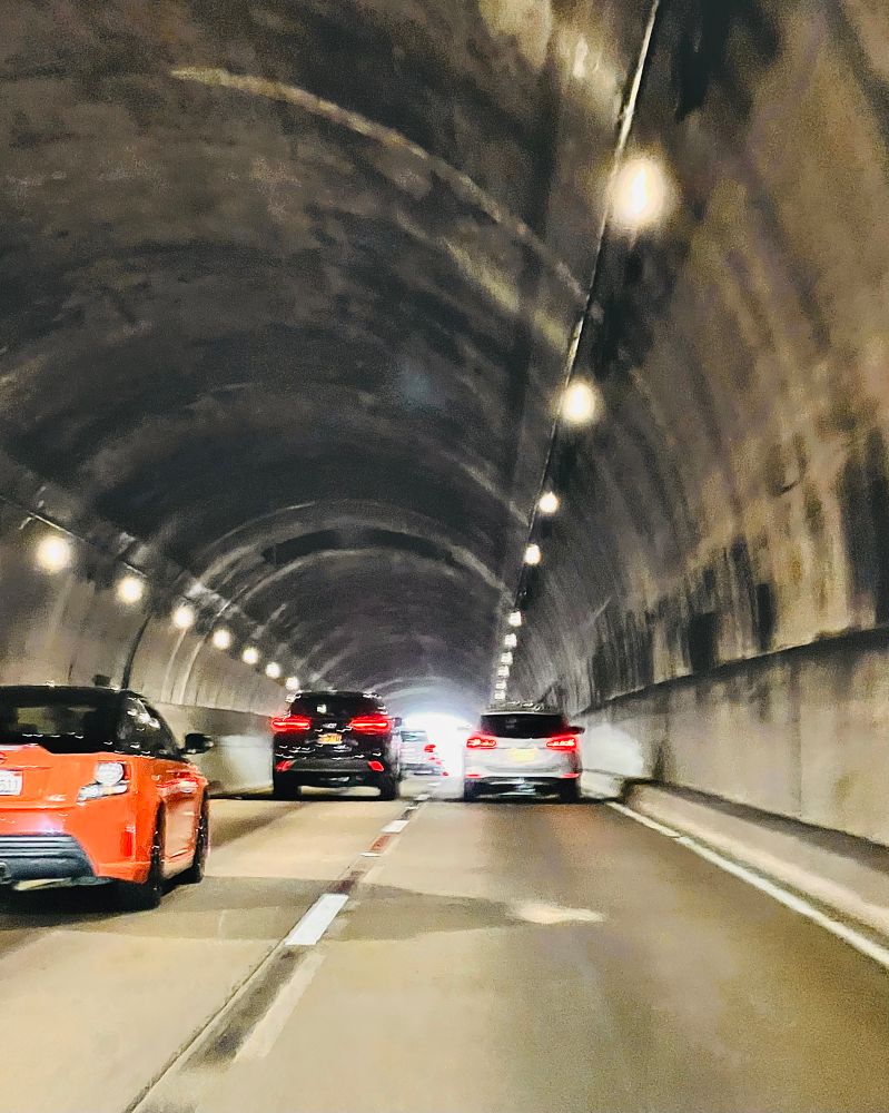 Cars inside of a lit up tunnel near the Golden Gate Bridge. 